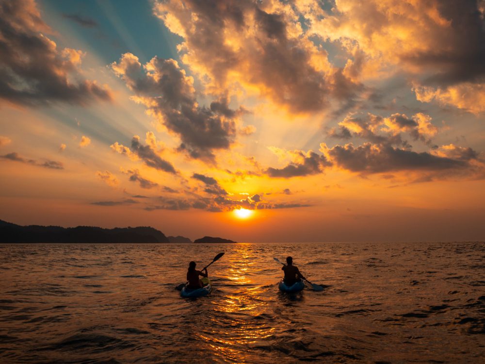Female and a male sailing with canoes close to each other at sunset A female and a male sailing with canoes close to each other at sunset