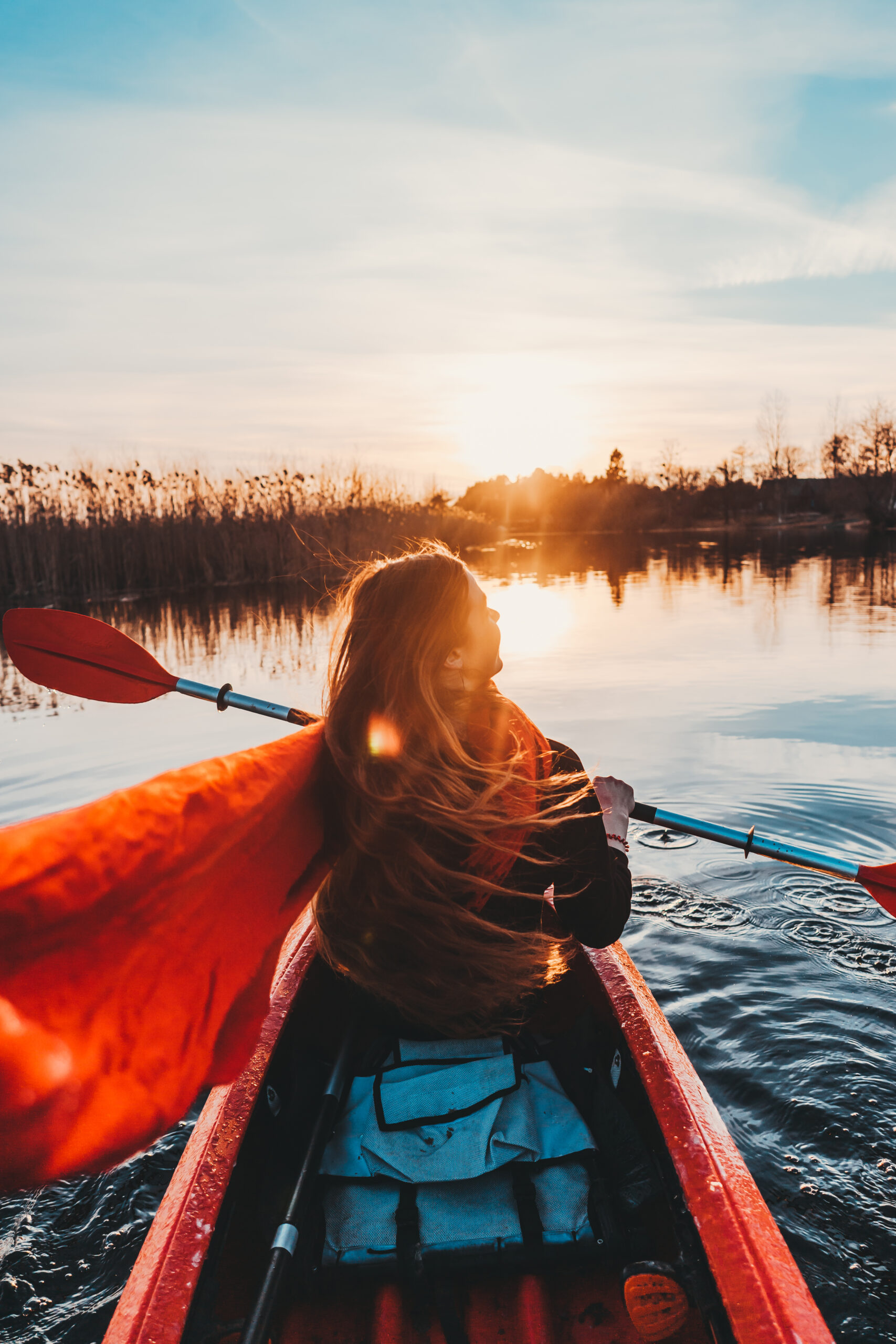 Back view of happy cute girl holding paddle in a kayak on the river Back view of happy cute girl holding paddle in a kayak on the river, enjoying a lovely summer day